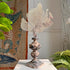 A hand-crafted wood and applied gesso altar vase, late 18th century with gilt rose silver finish, displayed on a tabletop with indoor plants and tapestry in the background.