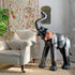 Decorative antique leather elephant figure in a living room setting with a floral curtain and white sofa.