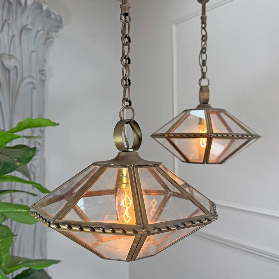 Two hanging vintage french glass lantern pendant lights with geometric faceted clear glass shades and antique bronze metal frames, shown in a softly lit interior setting.