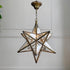 A geometric star-shaped pendant light with a bronze-finished metal frame and clear glass panels, hanging against a white paneled wall.