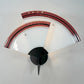 A vintage wall-mounted light fixture with two curved translucent white shades bordered in glossy reddish-brown and black, mounted on a black geometric base against a plain light gray wall.