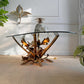 A decorative Maison Jansen console table with a clear oval glass top and a sculptural metallic base resembling leaves and branches, shown in a styled interior with a manetti pineapple ice bucket on top