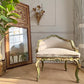 An ornate antique Venetain Italian chair with a carved gold and green frame, upholstered in cream velvet, set in a decorated room next to a large mirror and potted plant.