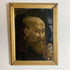 A framed antique oil painting on glass depicting a portrait of an elderly bearded man, housed in a distressed gold-colored wooden frame against a plain white wall.