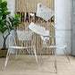 Mathieu Matégot vintage Perforated Sheet and Tubular Metal Chairs, arranged in front of a striped fabric backdrop with a potted green plant on the left.