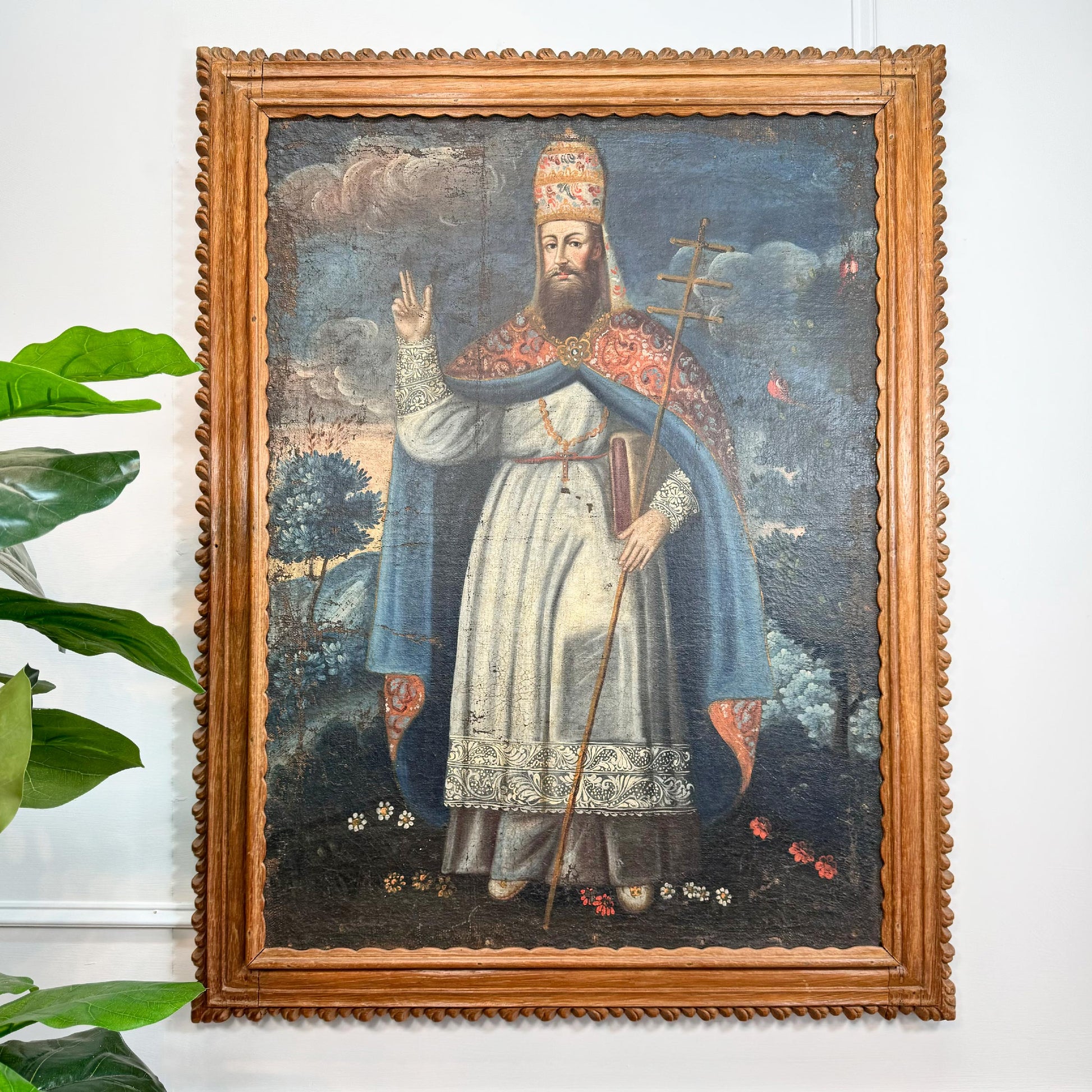 18th Century Cuzco School Oil Painting on Canvas Pope Gregory XIII in white and blue robes, holding a staff, displayed on a white wall with a green plant leaf visible at the left edge.