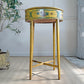 A vintage Italian Venetian oval side table with a distressed yellow painted finish and hand-painted floral motifs, set on a textured beige rug in a styled room.