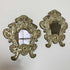 Pair Of European 18th C Silver Plated Baroque Mirrors with distressed silver repousse frames, displayed against a plain off-white wall.