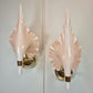 A pair of vintage Barovier and Toso wall sconces with glossy pale blush pink shell-shaped shades and polished gold metal bases, mounted on a light gray paneled wall.