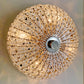 A round, ornate ceiling light fixture covered in clear faceted crystals and metallic gold-toned elements, viewed from directly above against a neutral light background.