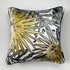 A square decorative silk pillow featuring a stylized tropical palm leaf pattern in gold, black, and gray on a white background, with a black piped edge.