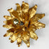 A gold leaf flower shaped wall sconce with a single bulb visible in the center, photographed against a plain light background.