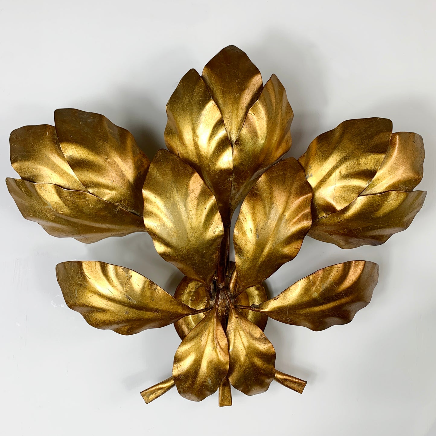 A vintage Hans Kogl metallic gold leaf wall light with multiple layered leaf shapes, photographed against a plain light gray background.