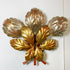 A vintage metallic wall decor piece shaped like a stylized flower with six leaf-like petals, featuring a gold center and silver-toned outer petals with coppery rust speckles, mounted against a plain white wall.
