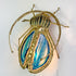 A Henri Fernandez Illuminated Gold Blue Agate Sculpture of a Longhorn Beetle beetle wall light with a gold metal frame and wings featuring blue, teal, and cream marbled patterns, shown against a plain white background.