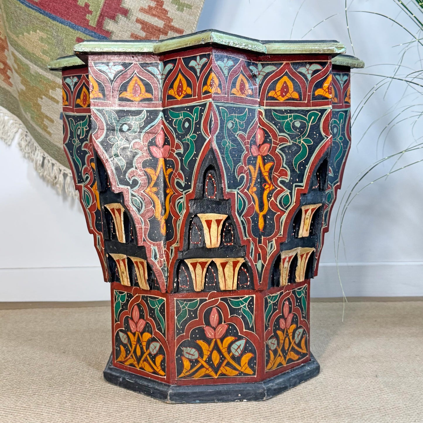 A decorative octagonal Moroccan Star wooden side table with intricate hand-painted Moroccan-style patterns in red, green, orange, and black, set against a neutral indoor background.