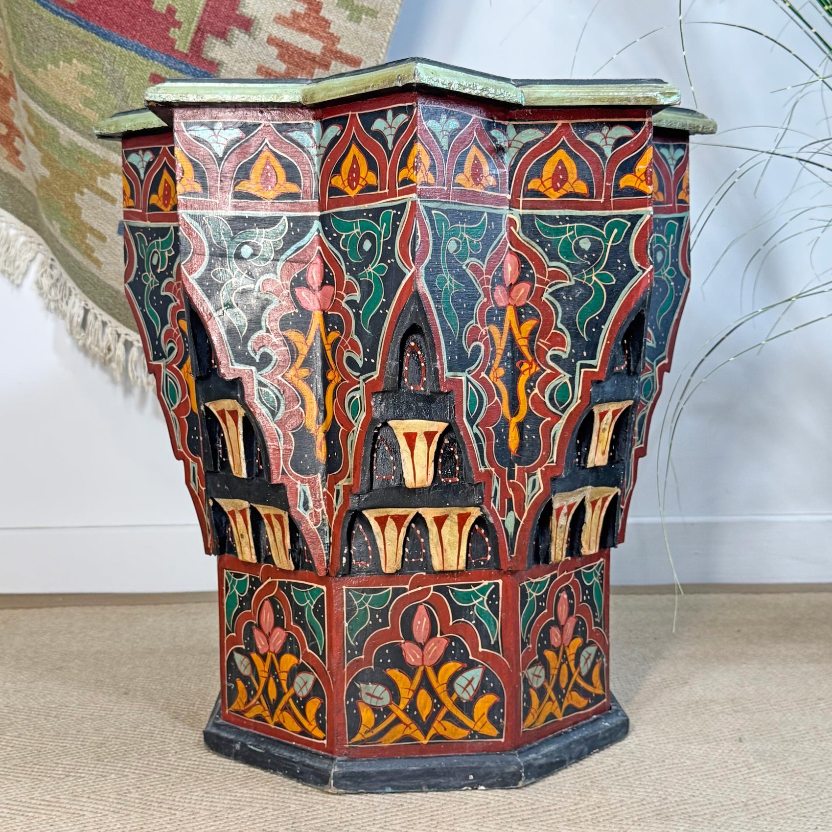 A decorative octagonal Moroccan Star wooden side table with intricate hand-painted Moroccan-style patterns in red, green, orange, and black, set against a neutral indoor background.