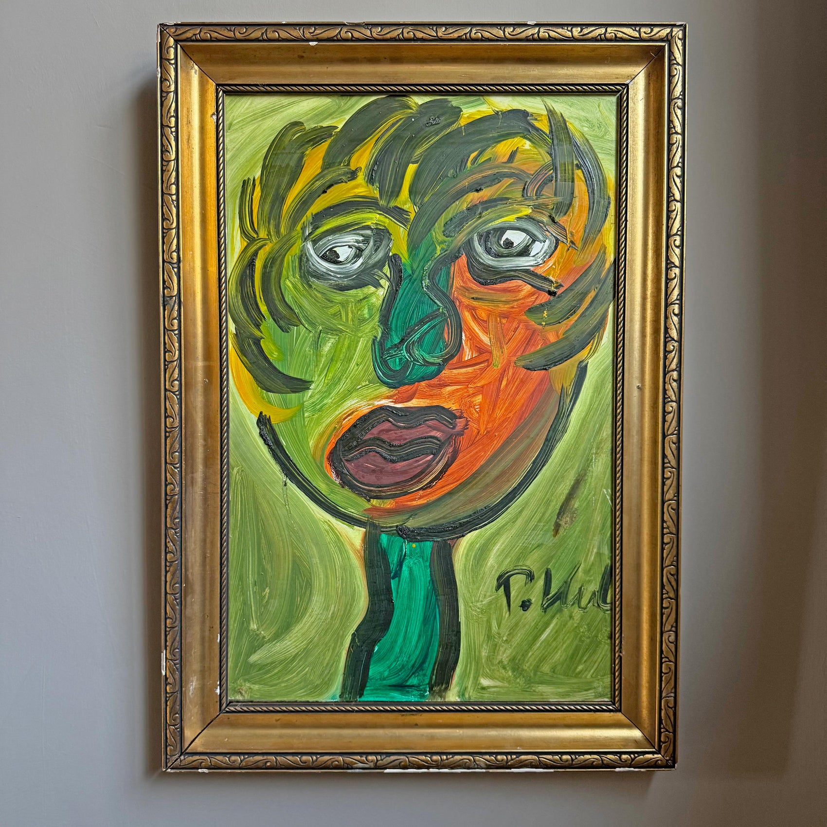 A framed Robert Keil abstract portrait painting of a face with expressive green, yellow, orange, and purple brushstrokes, enclosed in an ornate gold frame and hanging on a light gray wall.