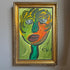 A framed Robert Keil abstract portrait painting of a face with expressive green, yellow, orange, and purple brushstrokes, enclosed in an ornate gold frame and hanging on a light gray wall.