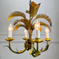 A vintage 1970s metal palm leaf chandelier with five candle-style bulbs, featuring a distressed gold and green metal finish with illuminated bulbs.