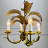 A vintage 1970s metal palm leaf chandelier with five candle-style bulbs, featuring a distressed gold and green metal finish with illuminated bulbs.