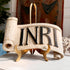 A decorative scroll-shaped wooden religious church carving with the letters &
