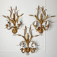 Three ornate Hans Kogl gold wall sconces with a wheat or reed-inspired leaf design, each holding two candle-style bulbs, mounted on a white paneled wall.
