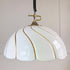 A vintage designer pendant light with a glossy white, petal-shaped shade accented by gold-toned metallic lines, suspended from a brass-colored ceiling mount with a black coiled cord.