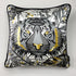A square decorative silk pillow featuring a stylized tiger face illustration in black, gray, white, and gold, with a black piped edge and a small black brand tag on the right side.