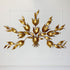 A decorative hans kogl gold leaf wall light in a leafy branch motif, mounted on a white paneled wall.