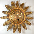 A decorative vintage sunburst wall sconce with a textured gold finish, featuring a central circular cutout medallion and radiating sculpted rays, shown against a plain white wall.