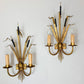 A pair of vintage bulrush wall sconces with gold-toned metal frames, candle-shaped bulbs, and black decorative accents, mounted on a plain white wall.