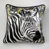 Square decorative silk pillow featuring a stylized black and white zebra print with gold accents, finished with a black piped edge, shown against a plain light gray background.